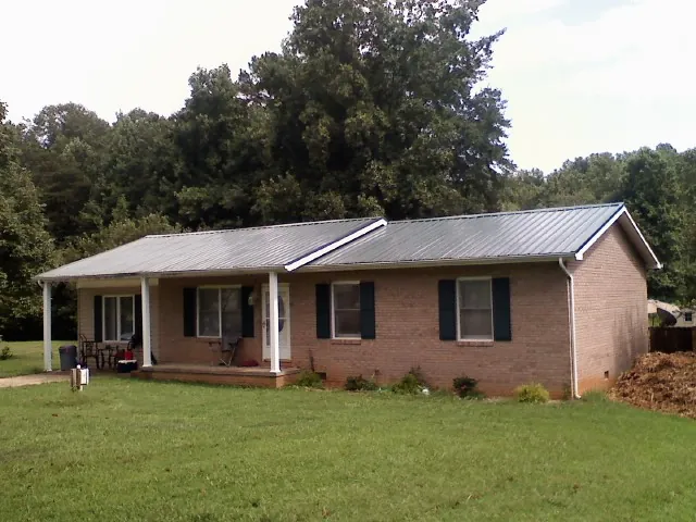 Gray metal roof on a brick ranch house with a side carport in Knotts Island