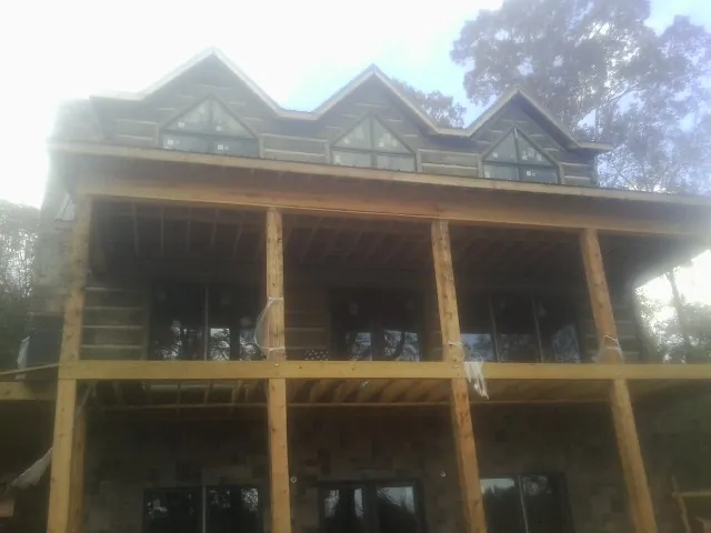 Dormers and porch framing on a large log home under construction — Roof Coating work by our crew in Knotts Island