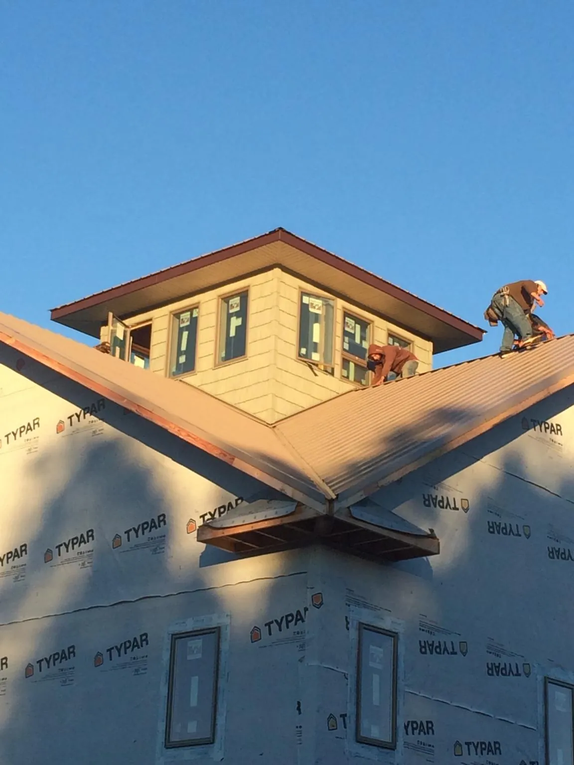 Roofers working around a rooftop cupola on a new metal roof at sunset — Roof Waterproofing in Knotts Island by Roofing Brothers